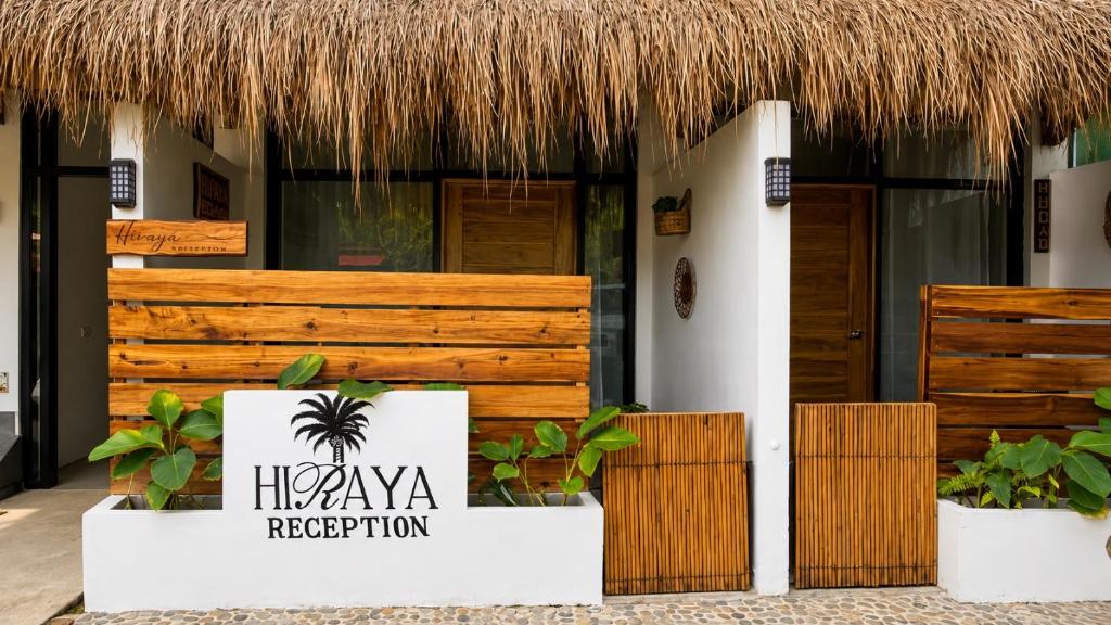 a hotel with a thatch roof and a sign at Hiraya Apartments in San Vicente