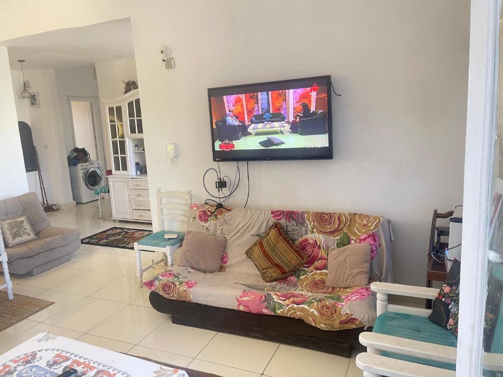 a living room with a couch and a tv on the wall at chalet ramsis village in Alexandria