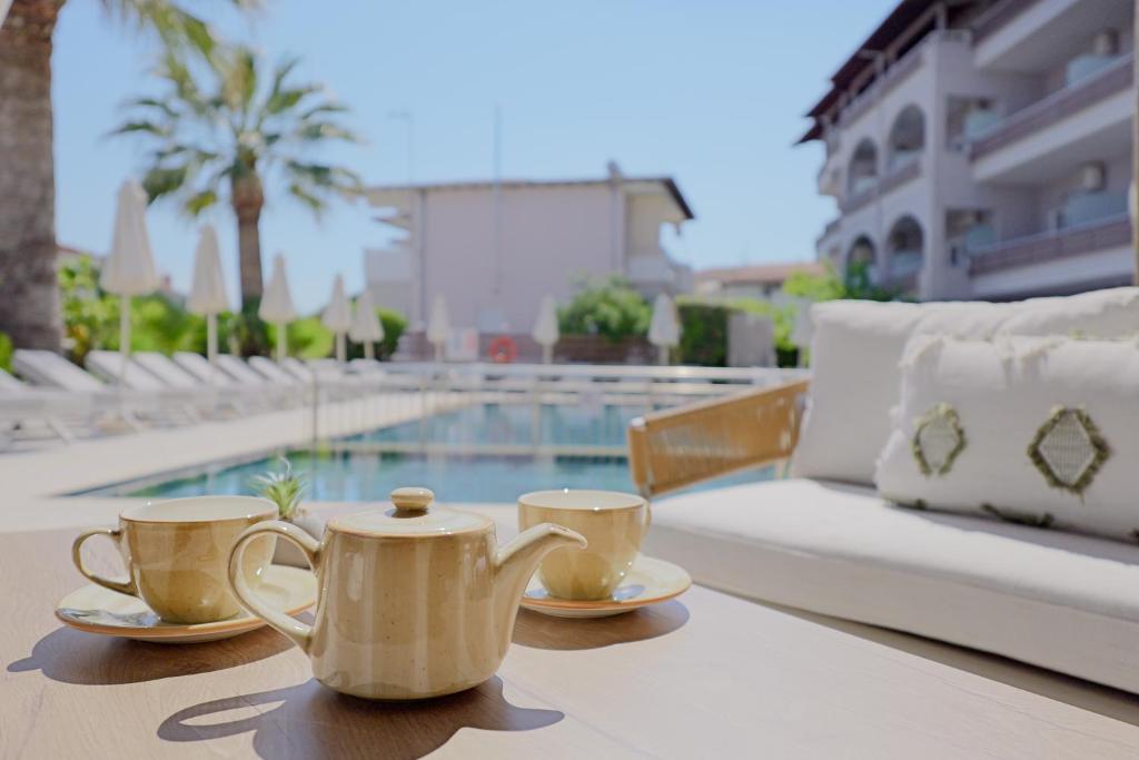 two tea cups on a table next to a pool at Hotel Tropical in Hanioti