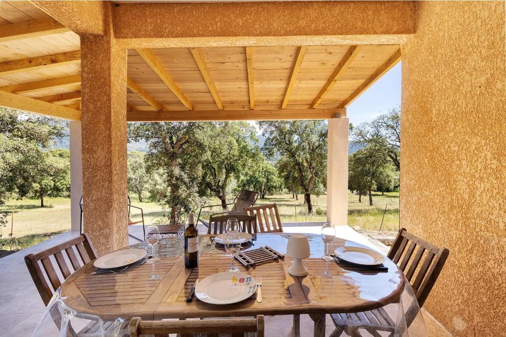 a wooden table with chairs and a wooden ceiling at Limbarto - Gîte climatisé au calme in Serra-di-Ferro