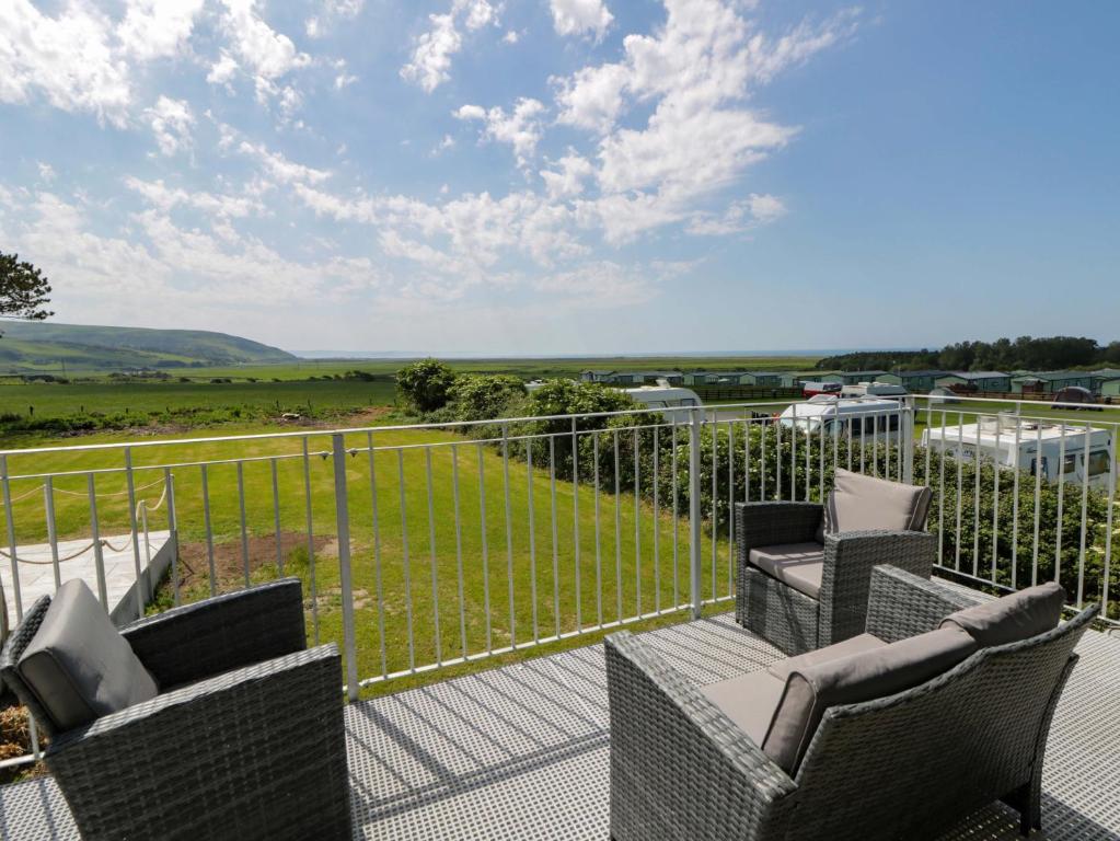 a patio with chairs and a fence with a view at Rosemary Cottage 2 in Tywyn