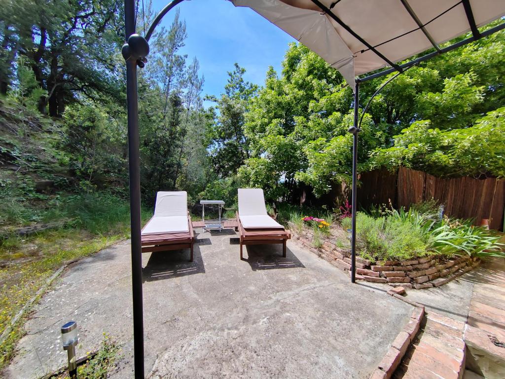 two chairs and an umbrella on a patio at Maison individuelle, au calme in Visan
