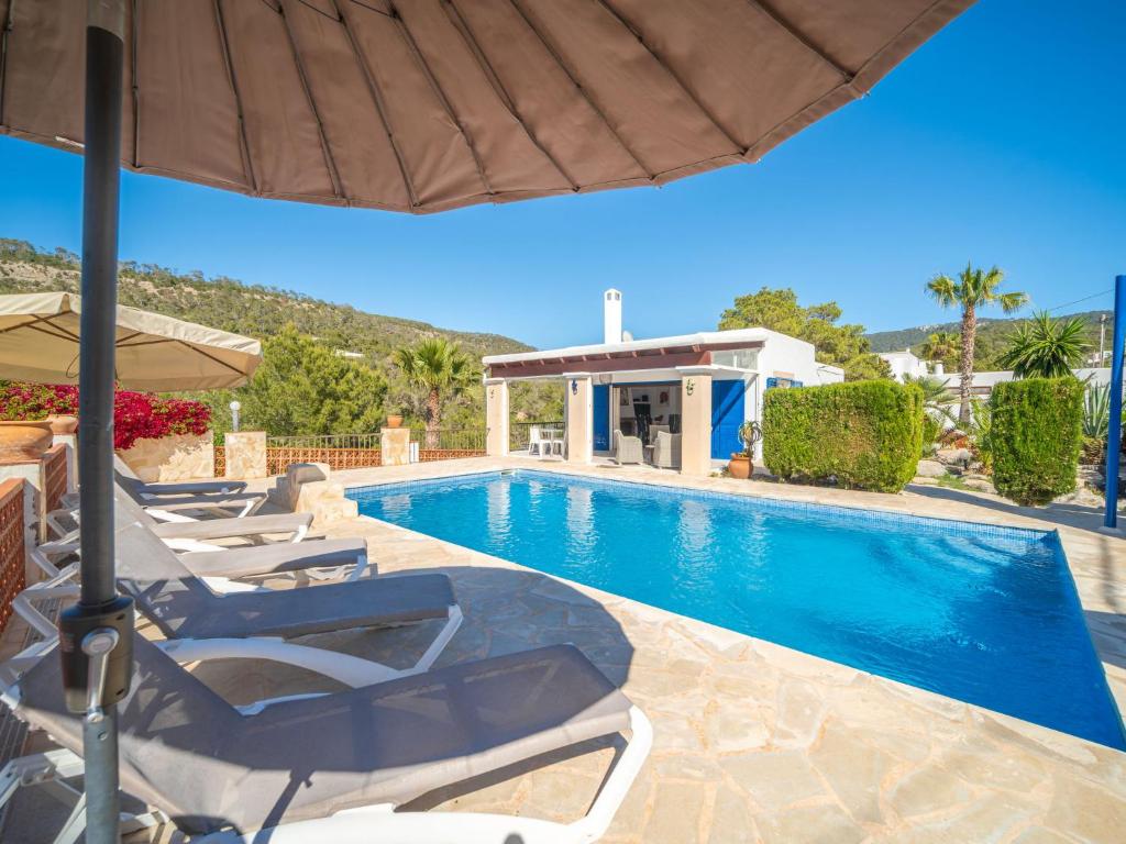 a swimming pool with lounge chairs and an umbrella at Holiday Home Anromi by Interhome in Cala Vadella