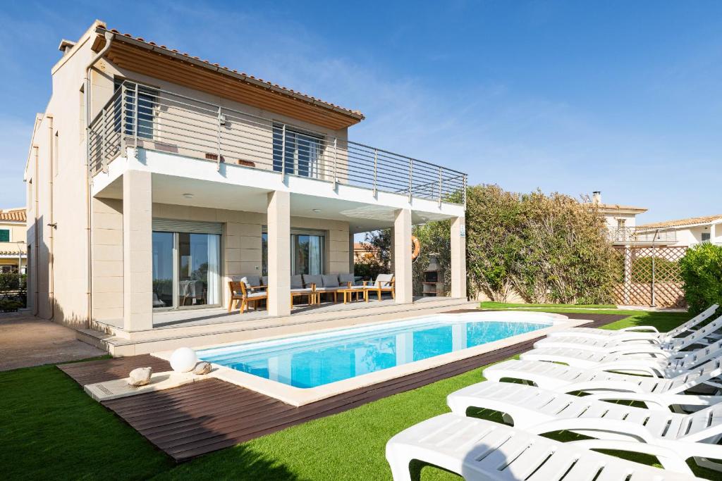 a villa with a swimming pool and white lounge chairs at Villa Ca'n Tugores by Rentallorca in Colonia de Sant Pere