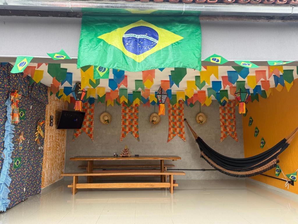 a room with a table and a flag and a bench at A 3,3 km do Parque do Povo in Campina Grande