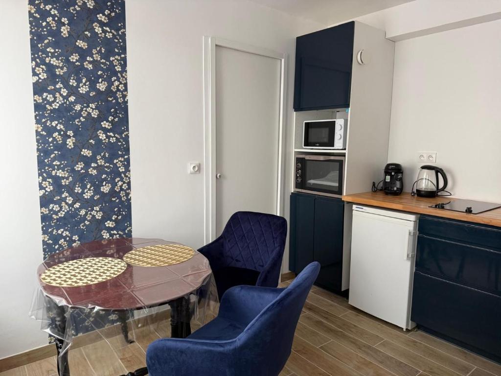 a kitchen with blue cabinets and a table and chairs at L'Opaline - Bord de Seine près de Giverny in Vernon