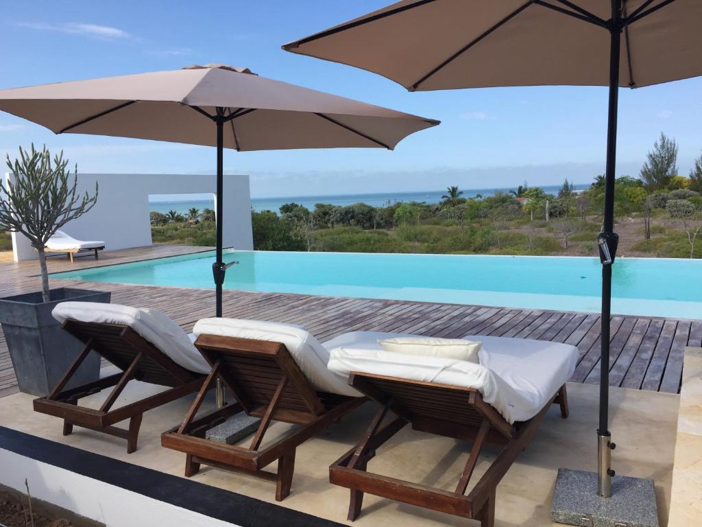 eine Terrasse mit 2 Stühlen und einem Tisch mit Sonnenschirmen in der Unterkunft Villa Claire in Toliara