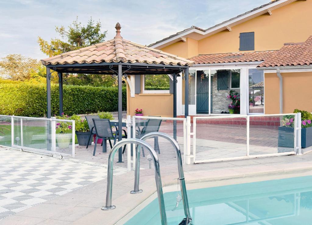 a swimming pool with a gazebo next to a house at Villa Marguerite in Coutras