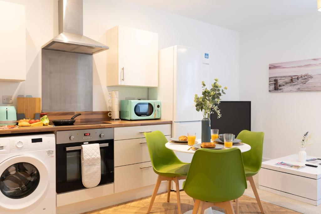 a kitchen with a table and green chairs in a kitchen at Derby Luxury Apartments - Curzon in Derby