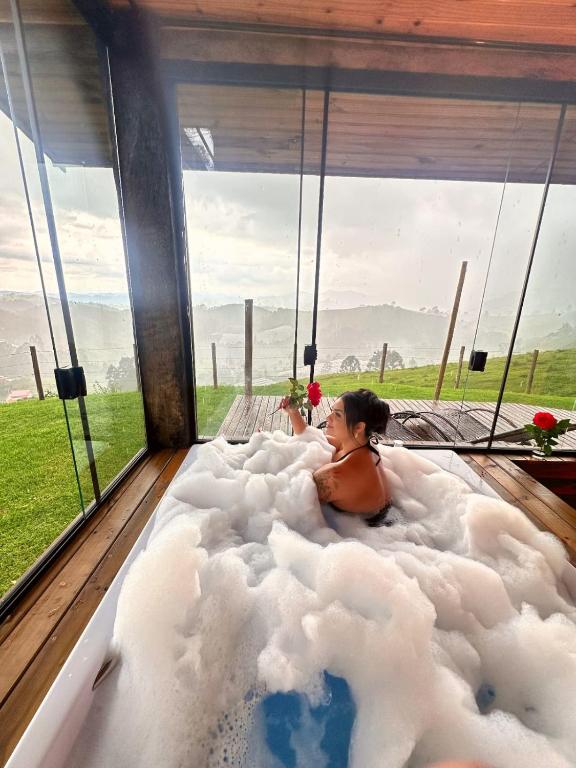 a woman laying in a cloud shaped bathtub at Chalé Vista do Paraíso in Gonçalves