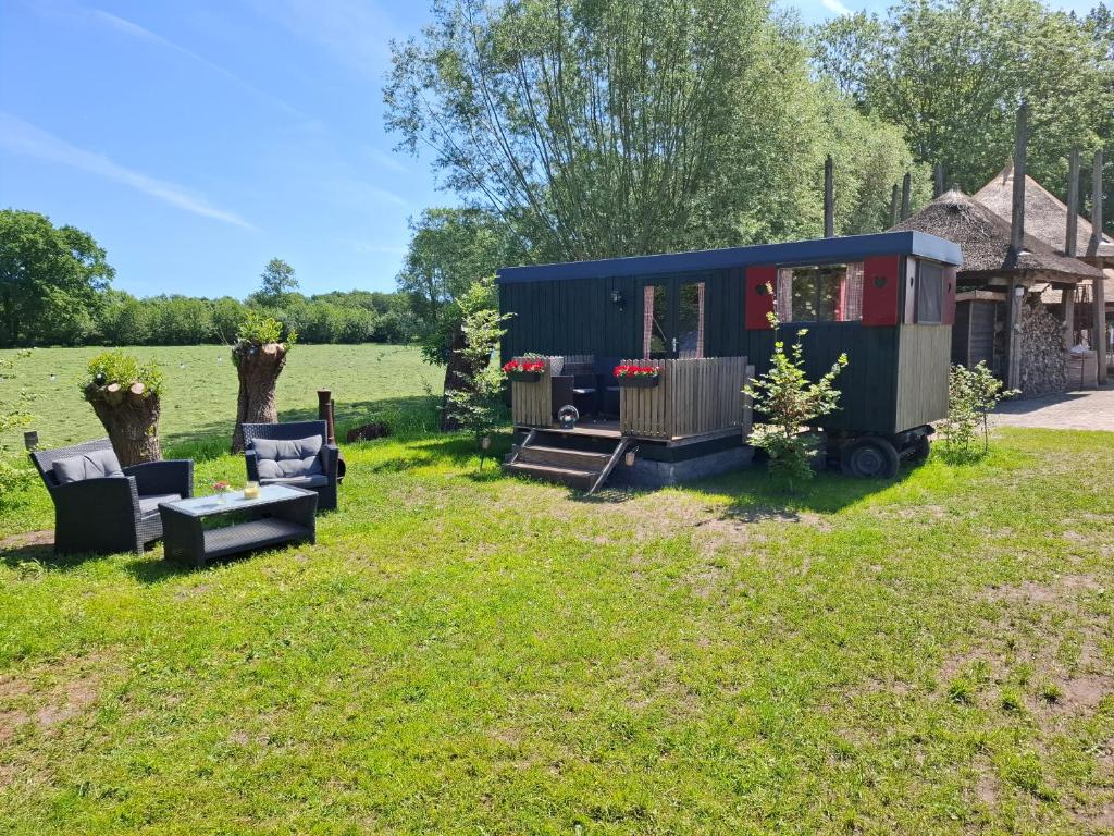 a tiny house in a field with furniture in the yard at Pipowagen 'klein Hoonhorst' in Putten