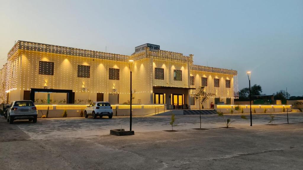 a large building with cars parked in a parking lot at Mount Green Hotel Bharatgarh in Bharatgarh