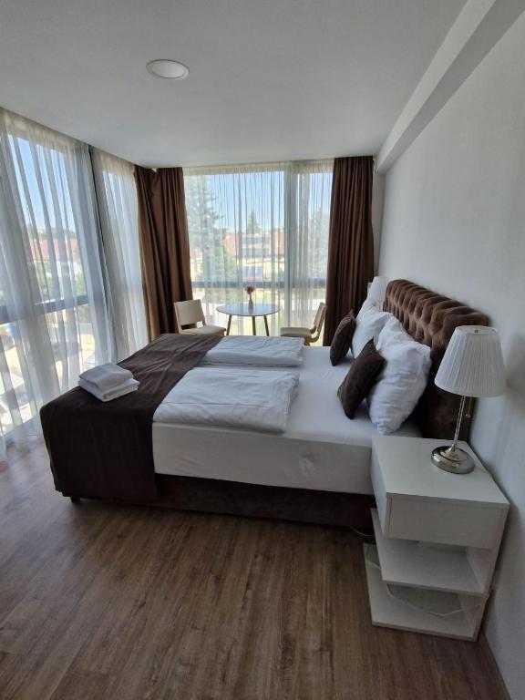a bedroom with a large bed and a large window at Gartenhotel Altmannsdorf in Vienna
