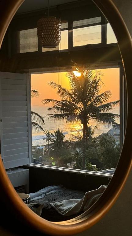 a view of a palm tree from a bedroom window at Umdloti Holiday Resort 208 in Umdloti