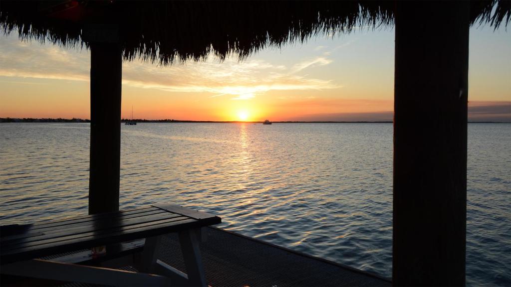 a sunset over the water from a hut with a bench at B405 Moon Bay in Key Largo