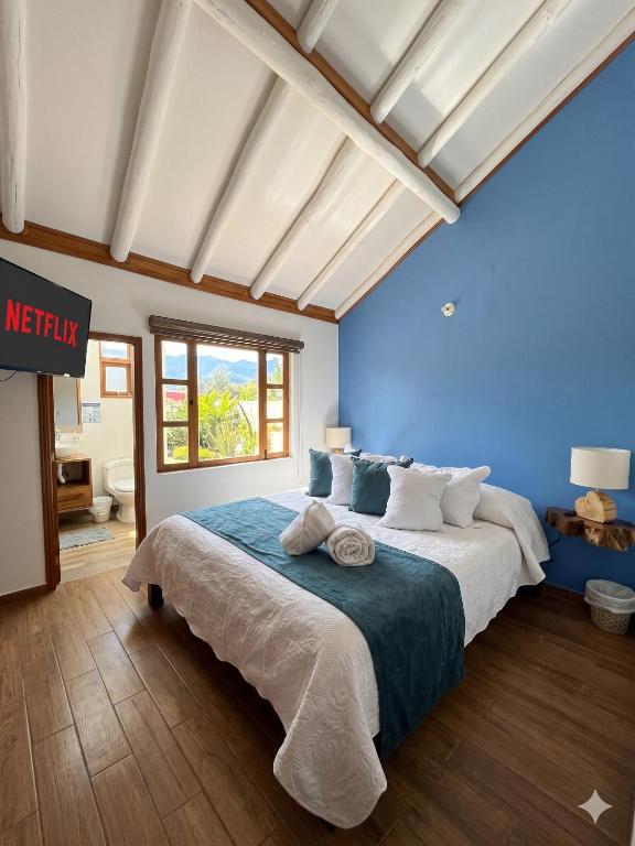 a bedroom with a large bed with blue walls at Casa Hotel Cenit in Villa de Leyva