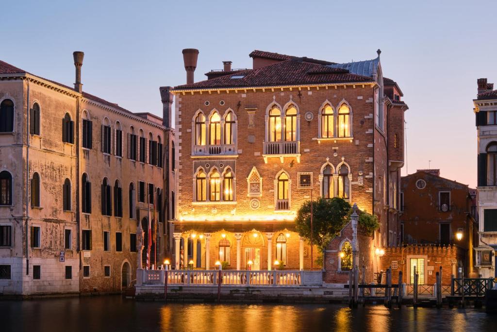 a large brick building with lights on a canal at Hotel Palazzo Stern in Venice