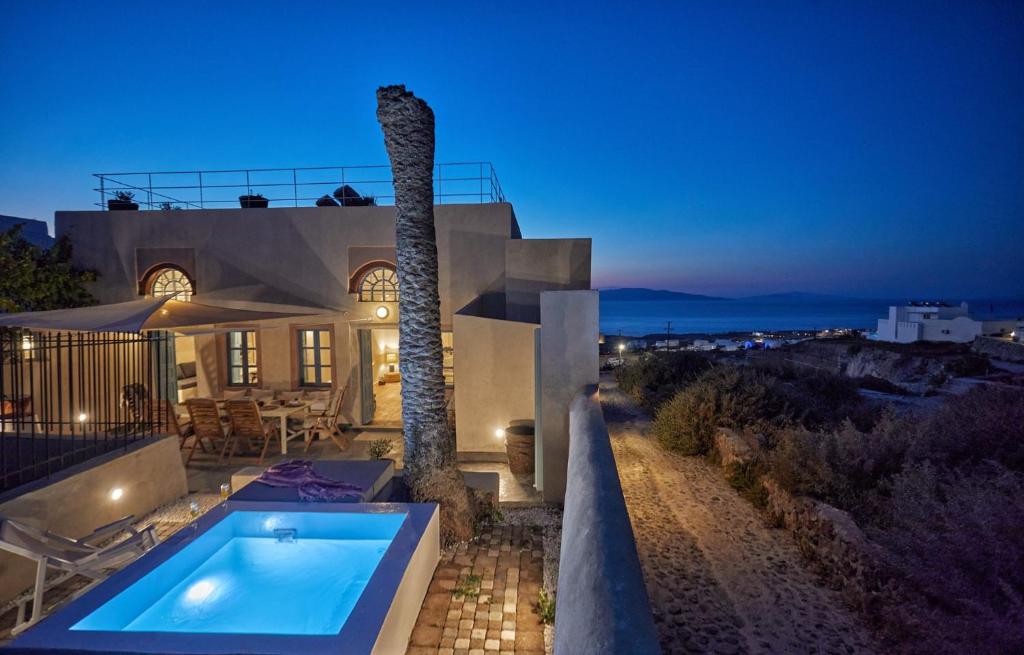 a house with a swimming pool and a palm tree at 318 Oia Villa in Oia