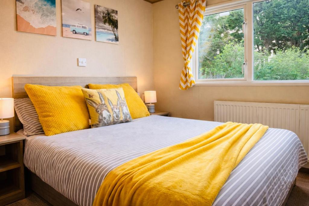 a bedroom with a bed with yellow pillows and a window at Peaceful Spot at Seton Sands 3-Bed Caravan near Edinburgh in Port Seton