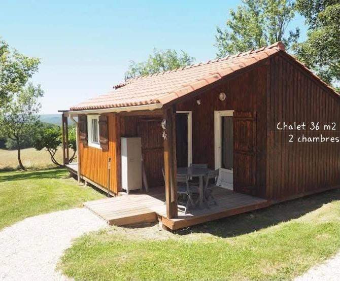 a small wooden house with a porch and a table at Chalets du Causse 2 in Gelle