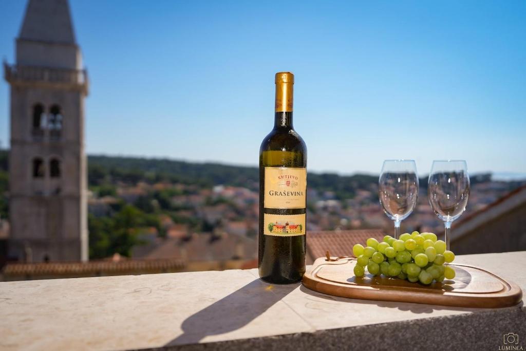 a bottle of wine and a plate of grapes on a table at Castello in Mali Lošinj
