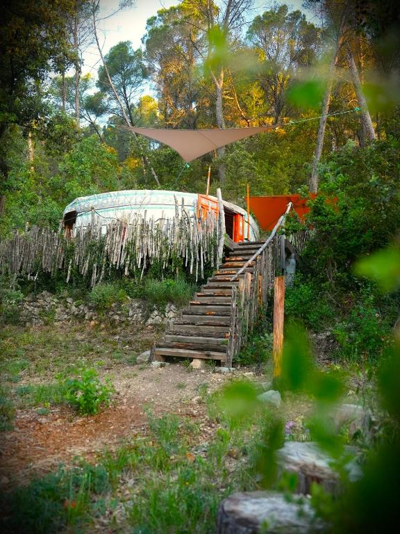 a boat sitting next to a staircase with a fence at Le Ptit Mas Yourte ou Logicube in Salernes