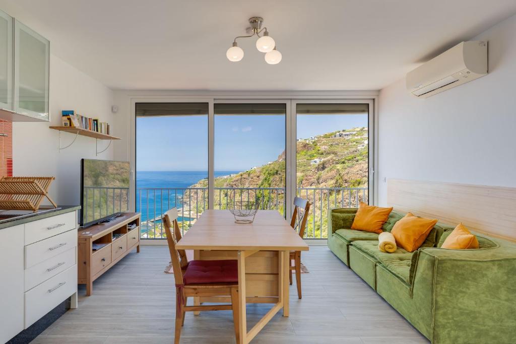 a living room with a green couch and a table at Studio SeaSky Tabua by Holiday Rental Madeira in Ribeira Brava