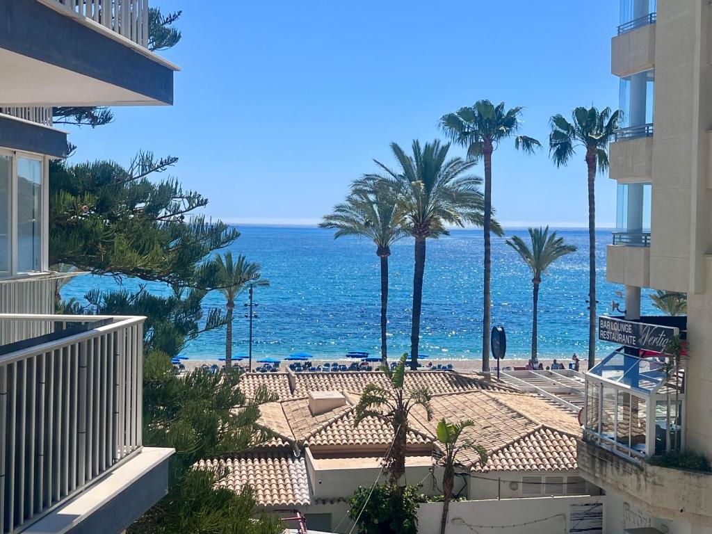 a view of a beach with palm trees and the ocean at Apartamento Blanco Albir in Albir