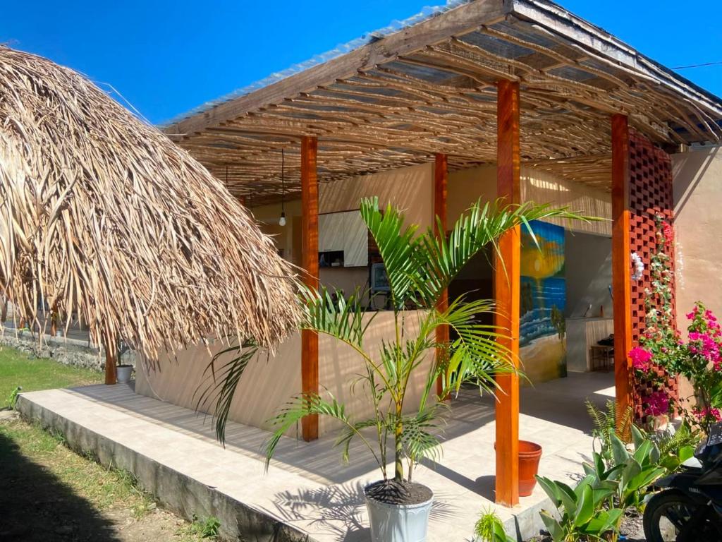 a tropical house with a thatched roof and plants at Wavez Lombok Hostel in Selong Belanak