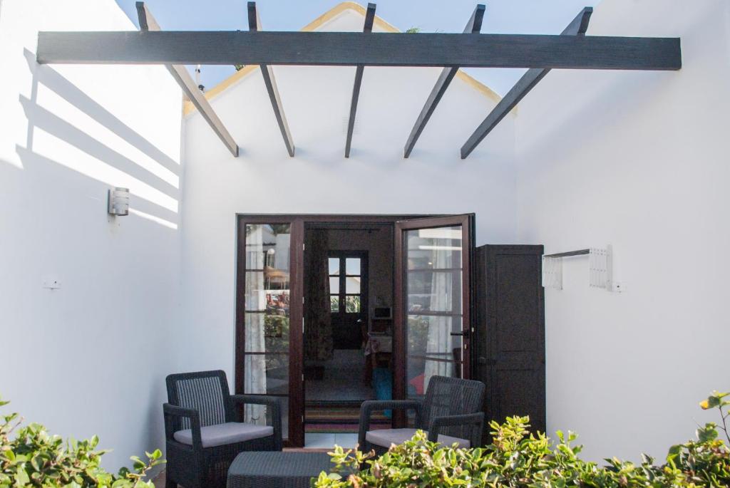 カレタ・デ・フステにあるBungalow Montecastillo 2の家の中に椅子と梁出し天井のあるポーチ