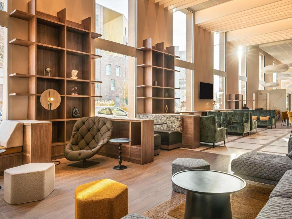 a lobby with couches and tables in a building at Mercure Achères St Germain en Laye in Achères