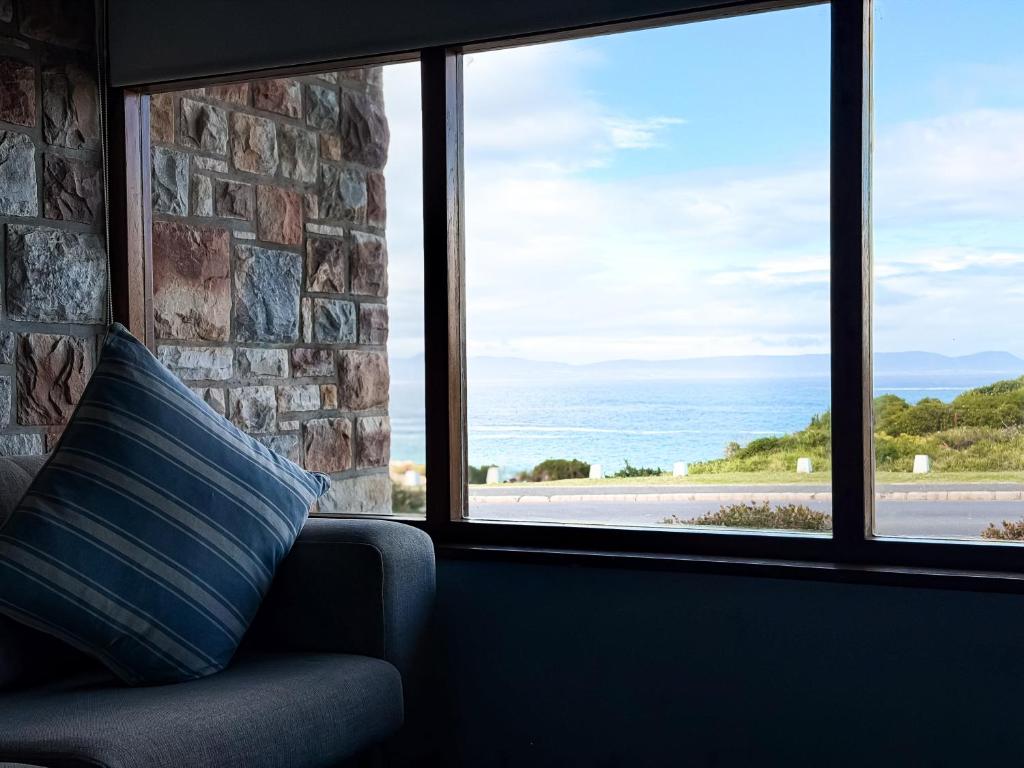 a couch with a pillow in front of a window at Normandie On Sea in Hermanus