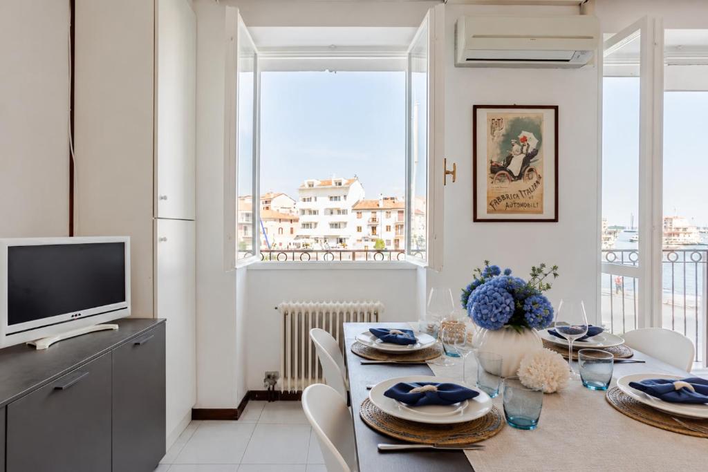a dining room with a table with chairs and a television at Harbour View Apartment - Elite Grado Centro in Grado