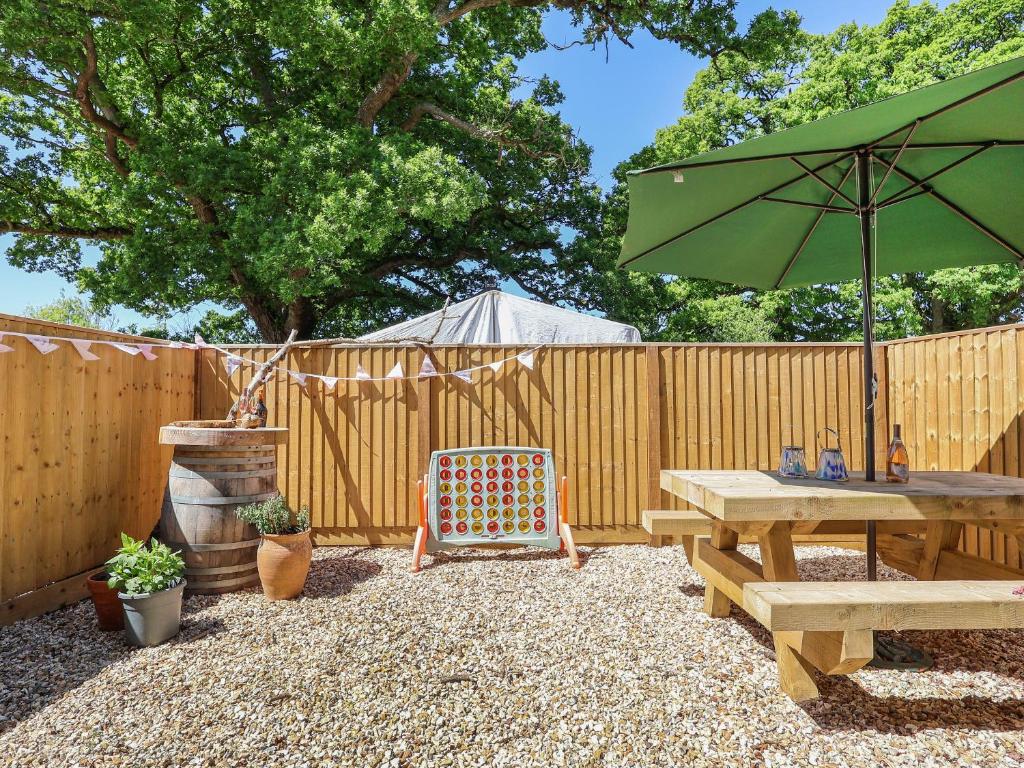 a wooden fence with a picnic table and an umbrella at Kendalls Nook in Shaftesbury