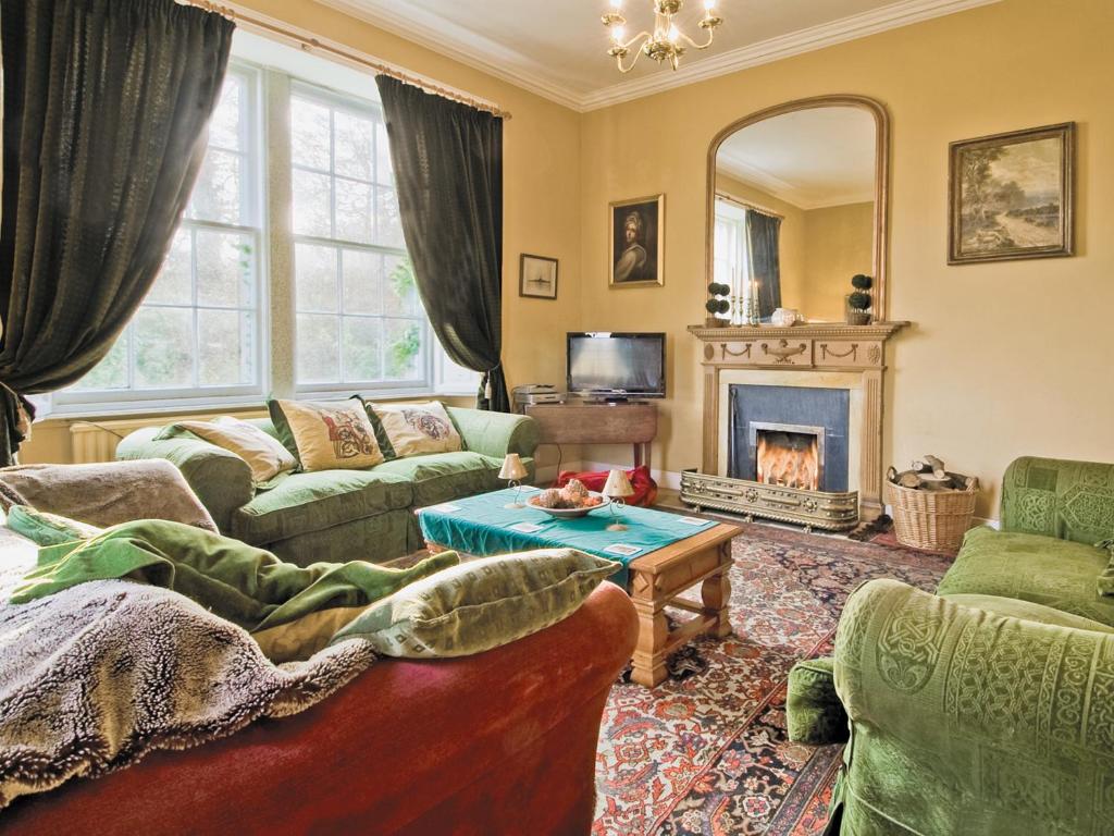 a living room with a couch and a fireplace at Lochside Garden House - S4484 in Town Yetholm