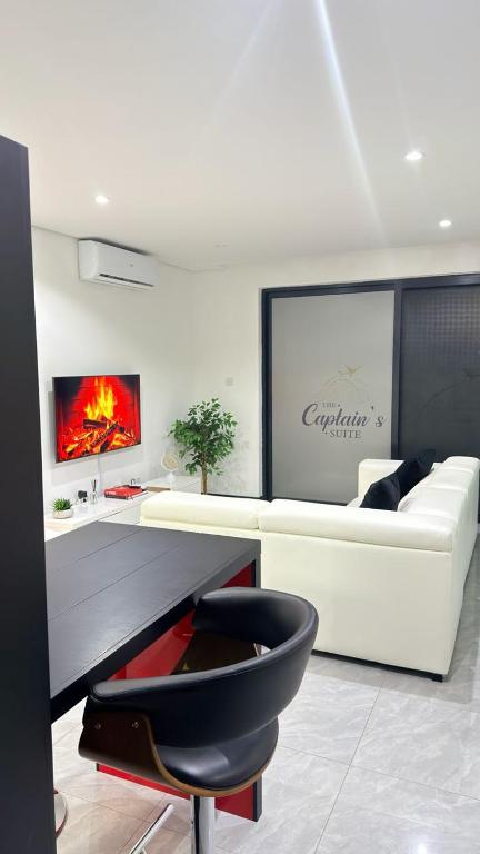 a living room with a white couch and a black chair at The Captains Suite in Gaborone