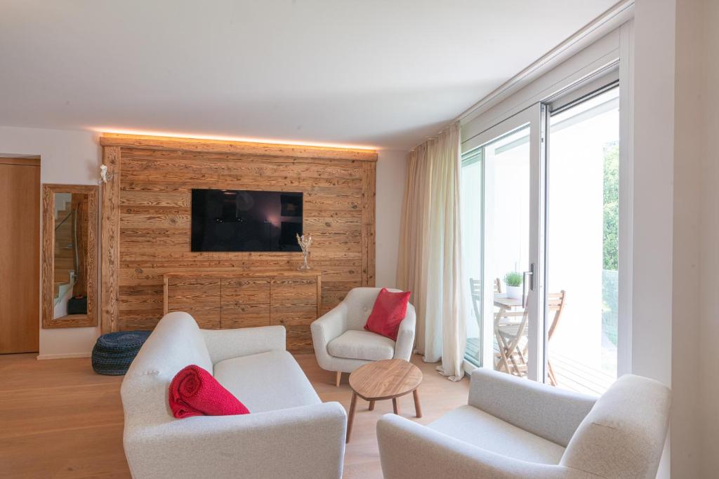 a living room with two white chairs and a tv at Residenza Edelweiss 5 3 in Sils Maria