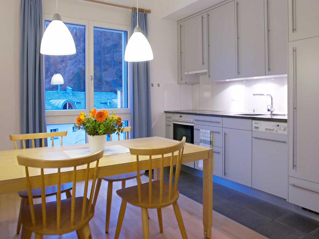 a kitchen with a wooden table and chairs and a sink at Residenza Alpenrose 22 in Sils Maria