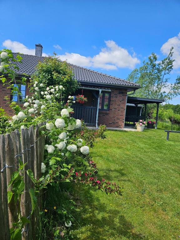 a house with a fence and flowers in the yard at Ferienwohnung - Wolkow in Wolkow