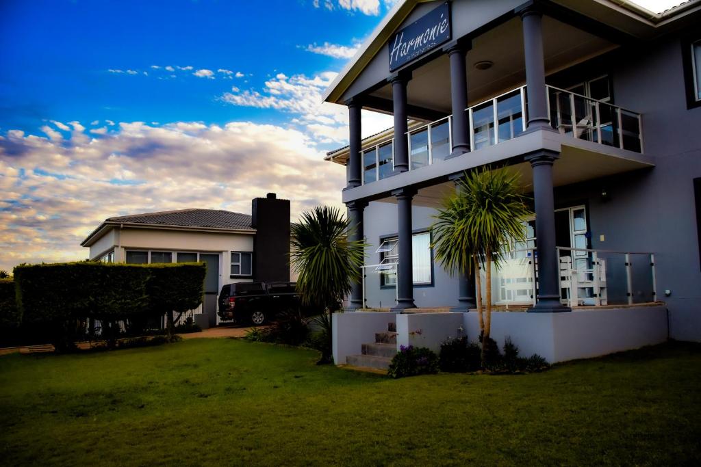 a white house with palm trees in front of it at Harmonie in Hartenbos in Mossel Bay