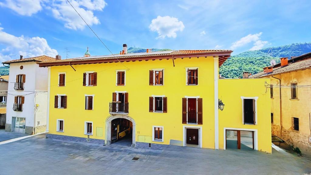 a yellow building in a city with mountains in the background at Residence Besano in Besano