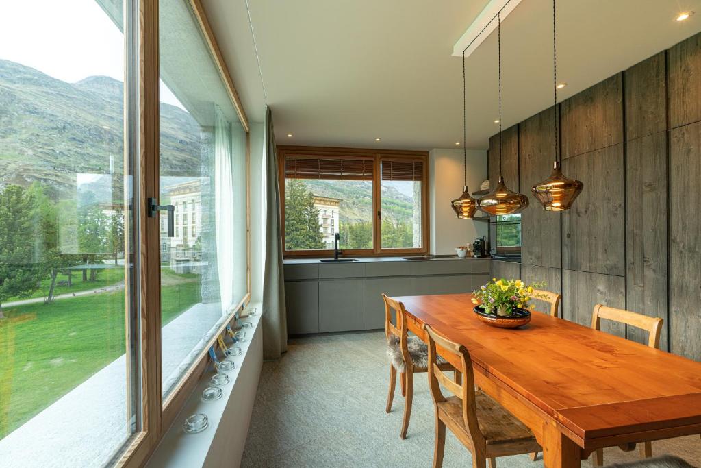 a dining room with a wooden table and a large window at Chesa Piol in Maloja