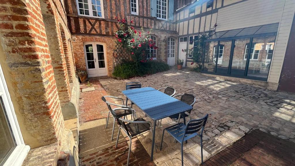 a blue table and chairs on a brick patio at Le Logis de Pélagie in Neufchâtel-en-Bray