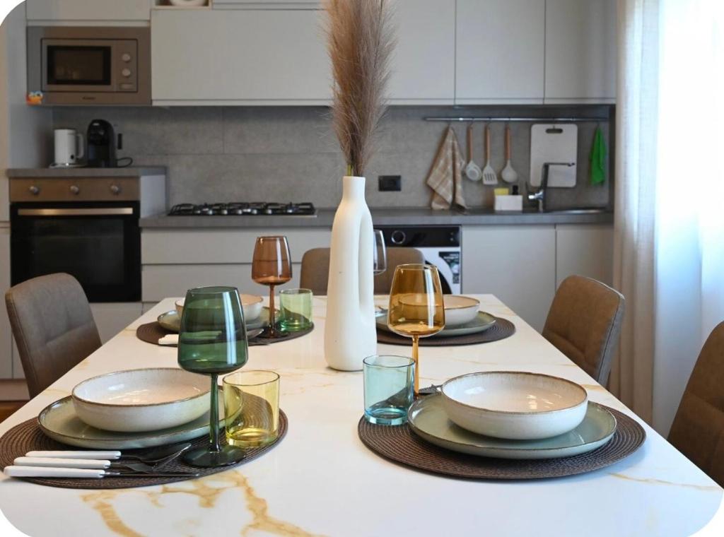 a dining room table with plates and glasses and a vase at Irpinia Maison in Quarto dʼAltino