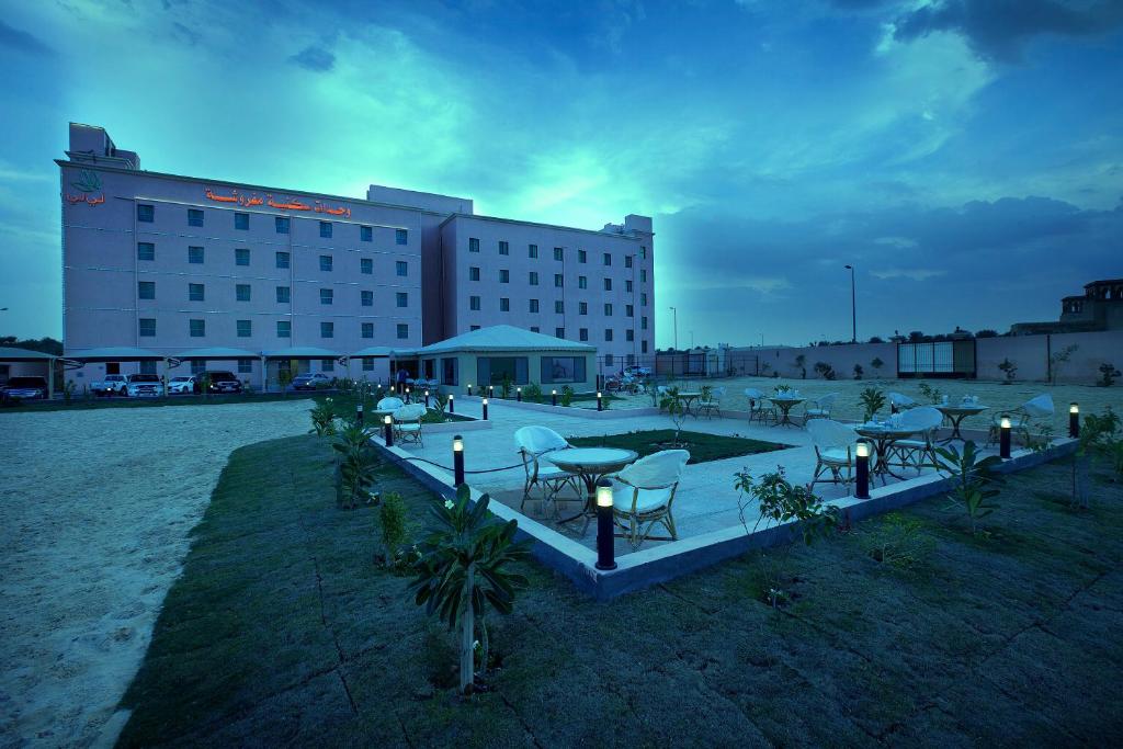 ein Gebäude mit einer Gruppe von Tischen und Stühlen in der Unterkunft Palms Lily Hotel Suites in Al-Hasa