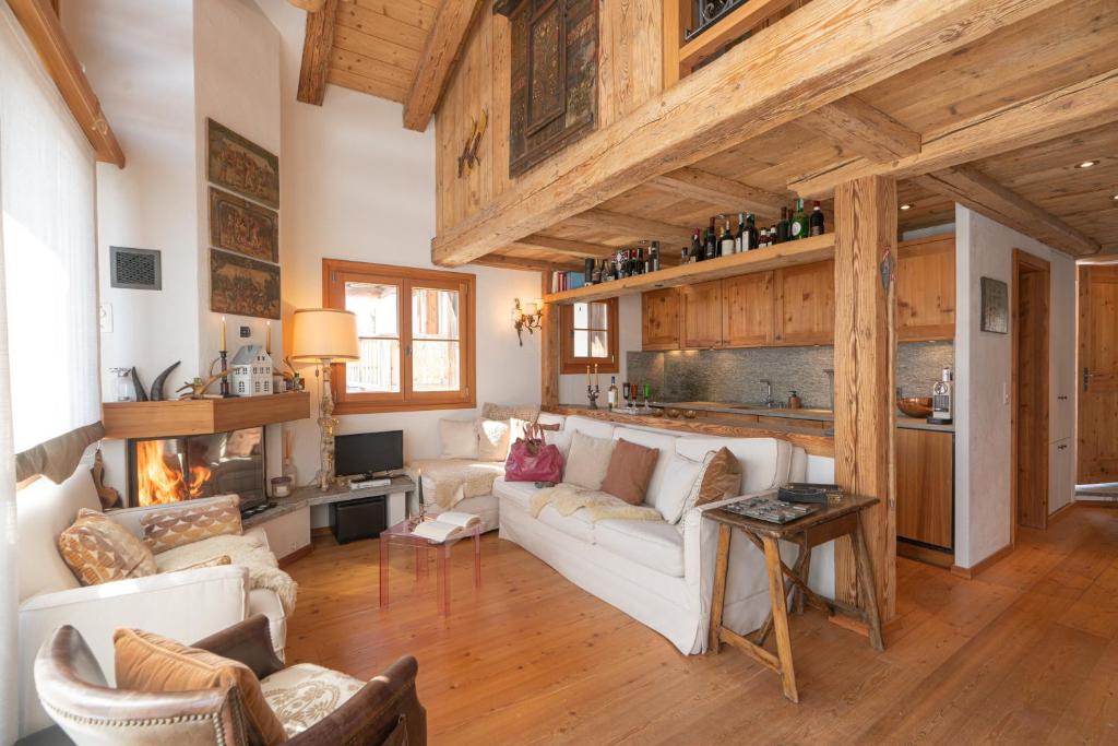 a living room with a white couch and a fireplace at Chesa Cavril in Maloja