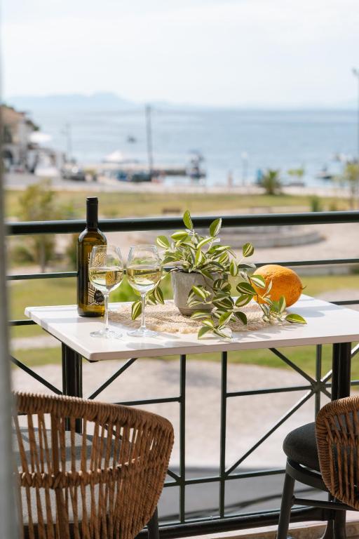 a table with two glasses of wine and a plant at Fissas Rooms in Syvota
