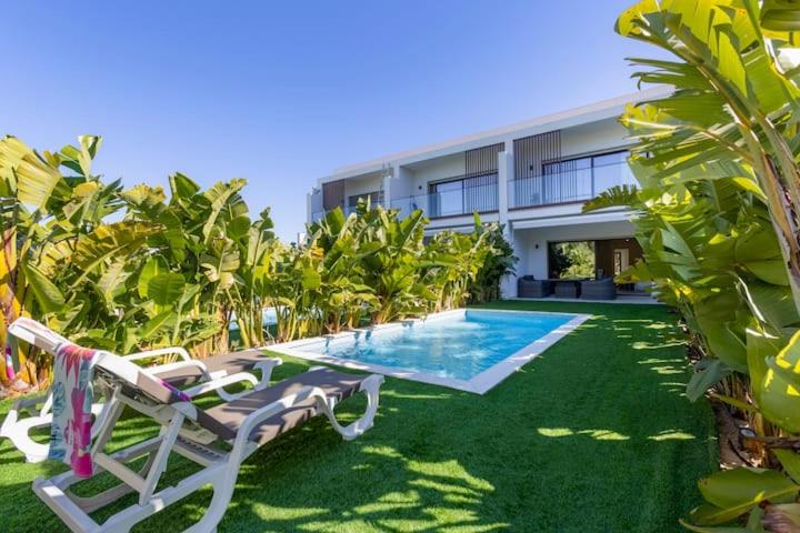 a villa with a swimming pool and two lawn chairs at Morada do Sol with Private Pool & Garden in Alvor