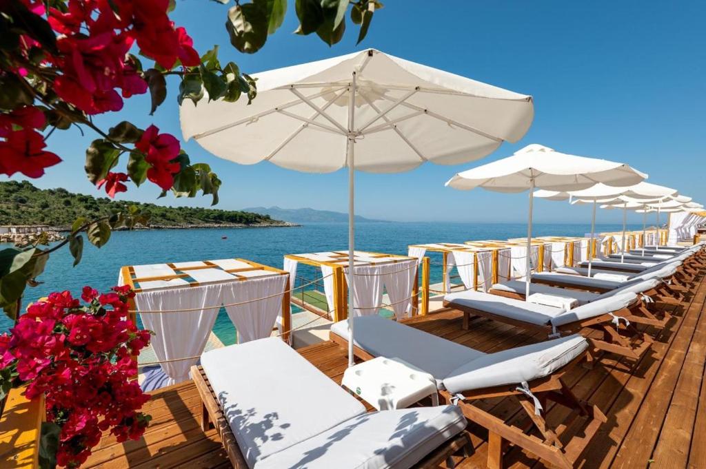 a row of lounge chairs and umbrellas on a beach at Cako Rooms Saranda in Sarandë