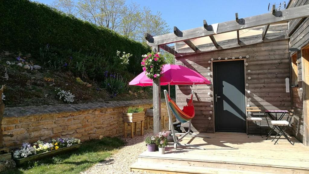 a woman sitting in a chair under a pink umbrella at Petite chambre confortable vignoble bourguignon in Brochon